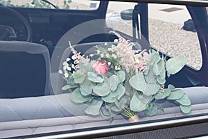 Marriage wedding flower bouquet in rear window bride car