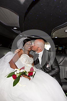 married bi-racial american couple in limousine wedding car