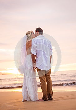 Married couple, bride and groom, kissing at sunset on beautiful