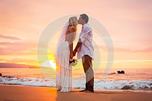 Married couple, bride and groom, kissing at sunset on beautiful