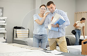 Married couple chooses and discusses mattress filling in furniture store