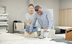 Married couple chooses and discusses mattress filling in furniture store