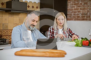 Married couple cooking on kitchen and using digital tablet