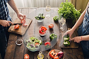 Married couple cooking together dinner vegetables salad in home