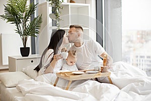 Married couple and daughter spending morning in bed