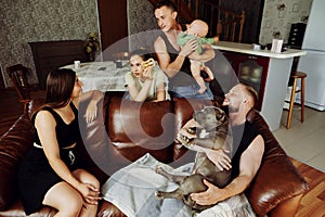 Married couple with dog, and young parents with their baby daughter are relaxing in country house.