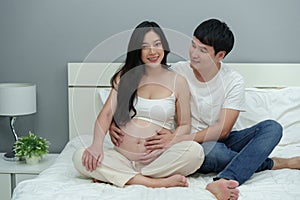 Married couple is expecting baby. man embraces his pregnant wife on bed