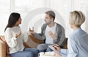 Married Couple Having Quarrel Sitting During Psychologist`s Appointment In Office