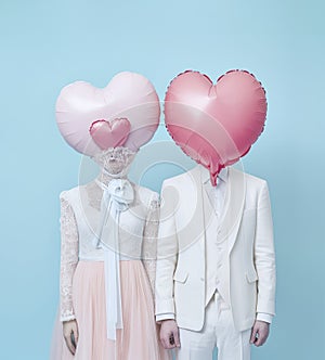 Married couple with heart shaped balloons in front of their faces.