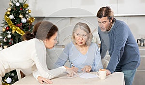 Married couple helps elderly mother write testament in kitchen at christmas