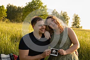 A married couple is holding an ultrasound scan showing their child