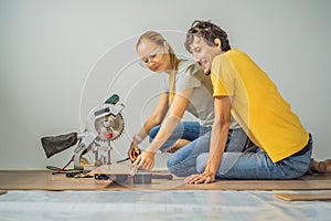 Married couple installing new wooden laminate flooring on a warm film floor. Infrared floor heating system under