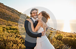 Married couple, kiss and cheek and smile in nature for honeymoon, travel or sunset adventure together. Happy groom and