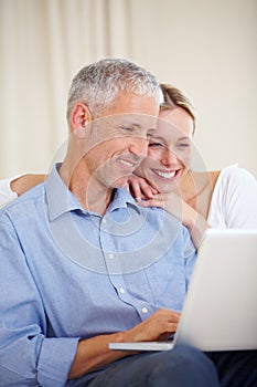 Married couple, laptop and video call with embrace, conversation and living room couch. Social media, technology and