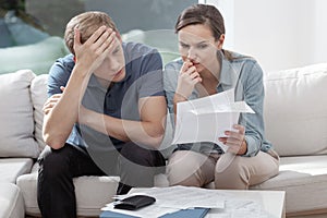 Married couple looking frustrated, having no money to pay off their debts, managing family budget together