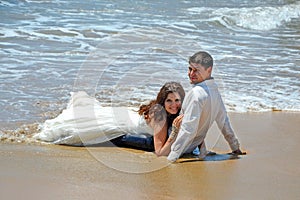 A married couple is lying on the sand on the beach of the Indian Ocean. Wedding and honeymoon in the tropics on the island