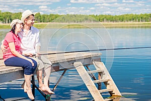 A married couple on a pier with bare feet catching a fish