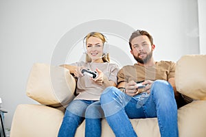 Married couple playing video games at home. Lifestyle and technology concept.