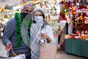 Married couple in protective masks with gifts at new year fair