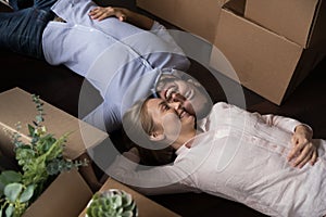 Married couple rest on floor on moving day, above view photo