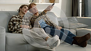 Married couple resting couch together. Redhead husband switiching tv channel