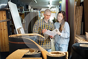 Married couple shopping at a hardware store checking list on paper