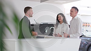 A married couple signs an order for the purchase of a car at a car dealership. Car salesman