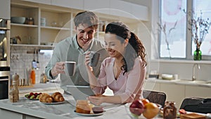 Married couple surfing internet having breakfast kitchen closeup. Family morning