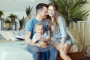 Married couple and their little baby baby in her arms. Young family at home in the morning on a day off. Joyful and happy faces