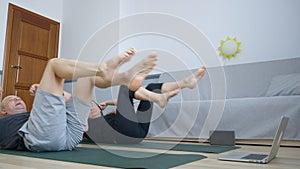 Married couple training abs on carpet online at home gym. Fitness man and woman training abdominal muscles by internet