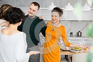 Smiling married couple welcoming guests for diner party at home