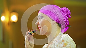 A married Jewess in front of a mirror paints the lips of a red pom