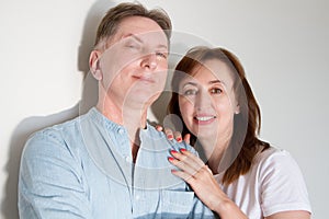 Married middle age couple isolated on white background. Wife hugging husband. Smiling family with healthy white teeth