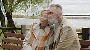 Married old couple healthy retired man woman Caucasian family middle-aged male hug mature female on bench in park