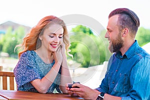 Marry me concept. Loving couple getting engaged in an outdoor cafe.