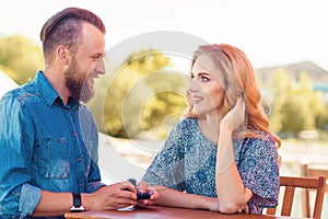 Marry me concept. Loving couple getting engaged in an outdoor cafe. Autumn background.