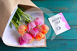 Marry me message note with engagement ring and flowers bouquet