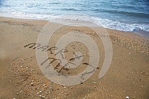 Marry Me written on sandy beach