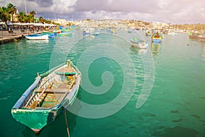 Marsaxlokk, Malta - Traditional colorful maltese Luzzu fisherboats at the old market of Marsaxlokk with green sea water