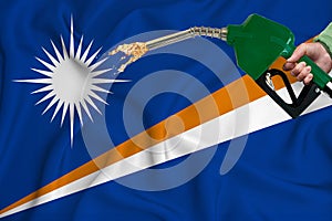 MARSHALL ISLANDS flag Close-up shot on waving background texture with Fuel pump nozzle in hand. The concept of design solutions.