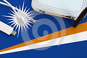 Marshall Islands flag depicted on table with internet rj45 cable, wireless usb wifi adapter and router. Internet connection