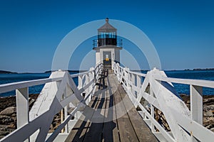 Marshall Point Lighthouse and walkway against a bright blue sky