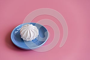 Marshmallow in a blue plate on a pink background. copy space
