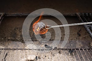 Marshmallow burning on fire over hot coals