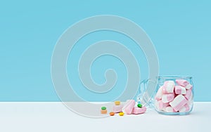 Marshmallow with dragee next to the glass open transparent jar and in it