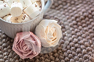 Marshmallow looks like rose close-up. cup with small marshmallows sprinkled with grated chocolate on cotton knitted napkin