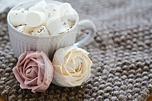 Marshmallow looks like rose close-up. cup with small marshmallows sprinkled with grated chocolate on cotton knitted napkin