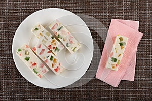 Marshmallow with marmalade in plate, marshmallow on paper napkin on mat. Top view