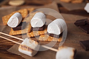 marshmallows, chocolate and cookies for making smore on brown background. view from above. copy space