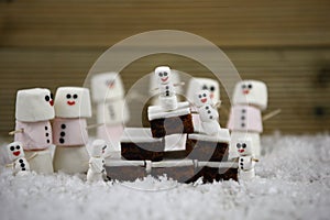 Christmas food photography picture of traditional cake and marshmallows shaped as snowman with icing used for the smiles